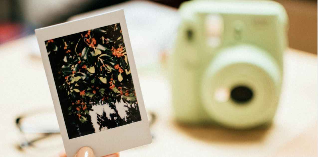 green polaroid camera with one polaroid picture